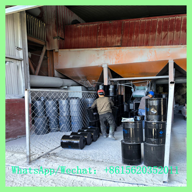 Factory workers handling and stacking China calcium carbide 50-80mm drums in production facility