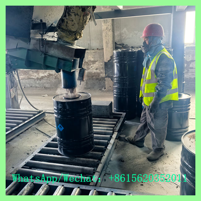Worker filling calcium carbide 50kg drum on automated production conveyer belt