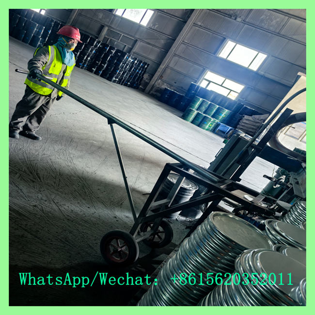 Factory worker operating manual cart to transport drum lids at calcium carbide supplier facility