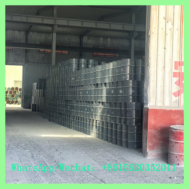 A large warehouse stocked with many dark industrial chemical drums containing Calcium Carbide (CaC2). Contact for bulk purchase via WhatsApp/Wechat: +8615620352011
