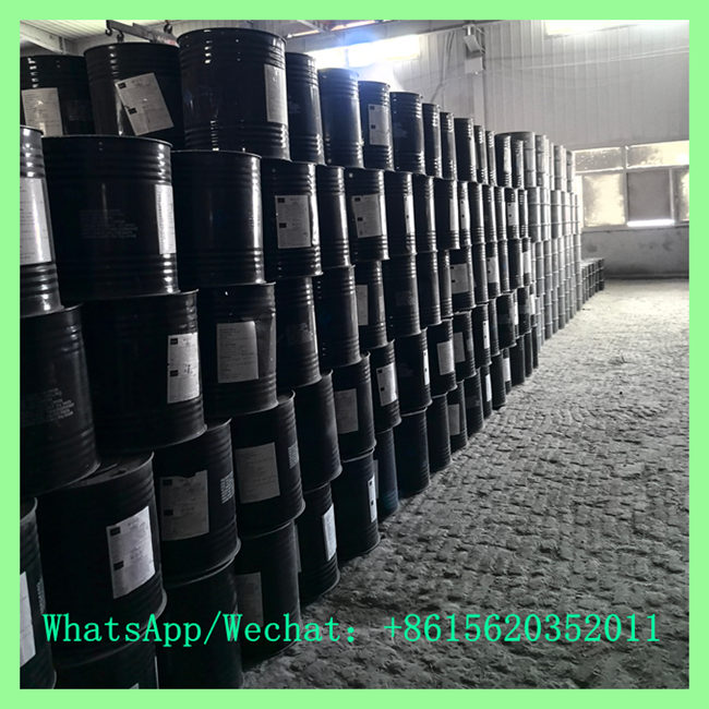 Industrial warehouse with a towering wall of black steel drums filled with high-purity 7-15mm calcium carbide. Contact: +8615620352011
