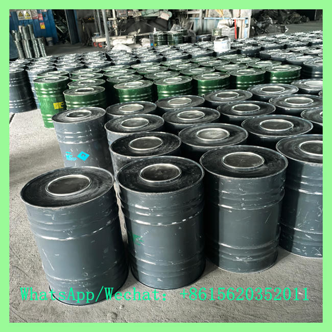 High-angle view of multiple rows of sealed black metal chemical drums arranged on a warehouse floor.