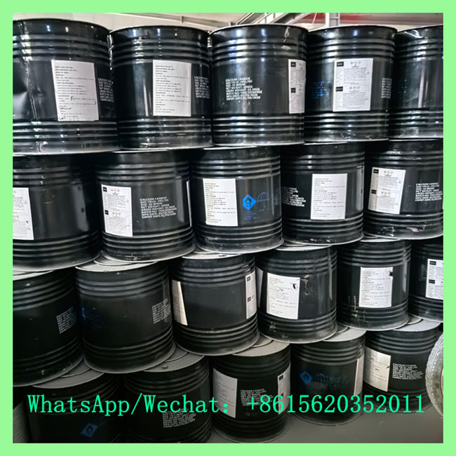 Close-up view of stacked black metal drums showing white specification labels and blue safety warning symbols.