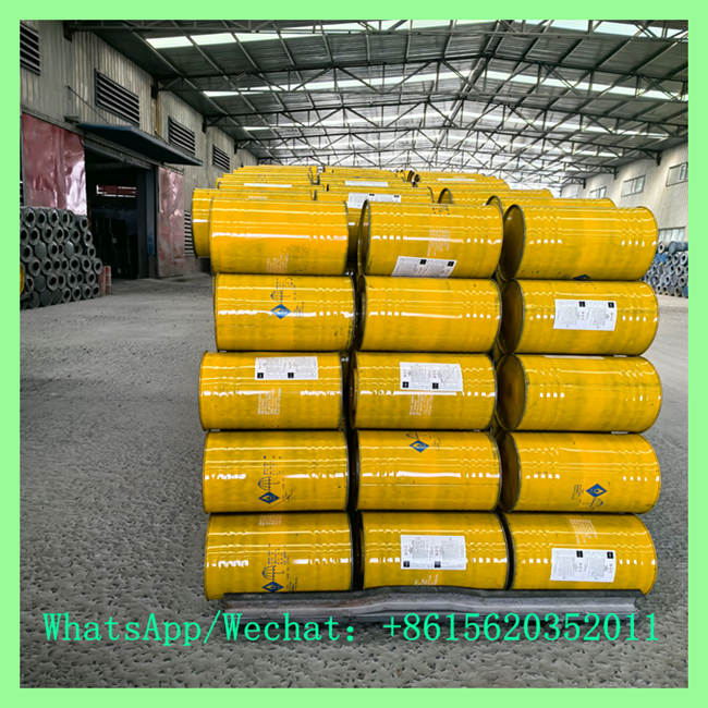 Stacked rows of bright yellow industrial chemical drums stored horizontally inside a spacious warehouse facility.