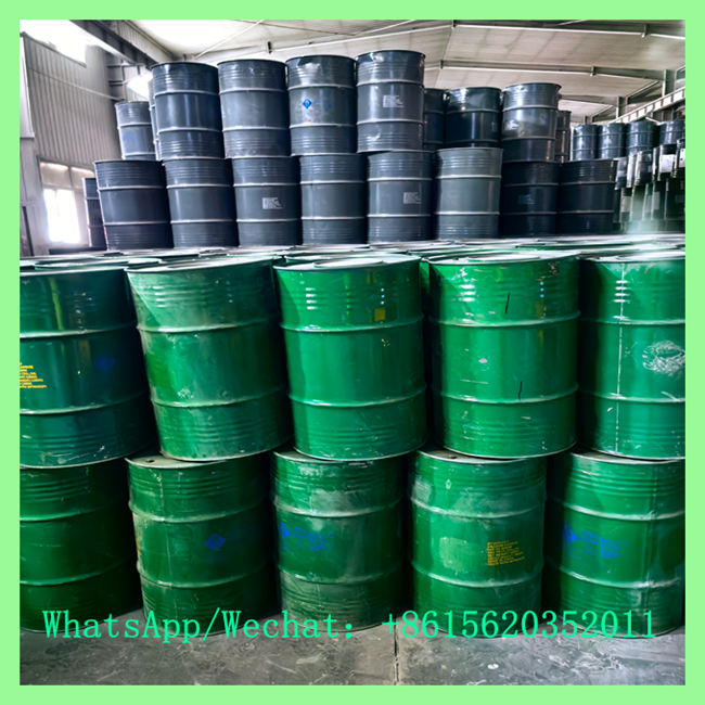 Multiple rows of green steel drums arranged in the foreground with dark grey industrial drums stored behind them.