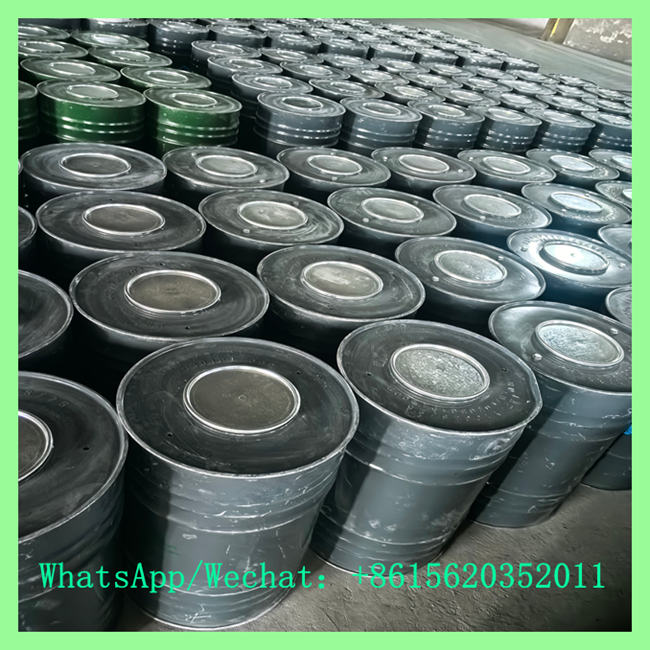 High-angle view of multiple sealed metal drums organized in tight rows inside a storage warehouse.