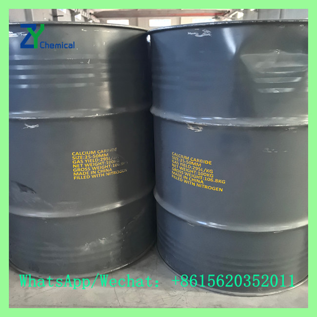 Grey metal drums with yellow stenciled text specifying calcium carbide lumps size 25-50mm