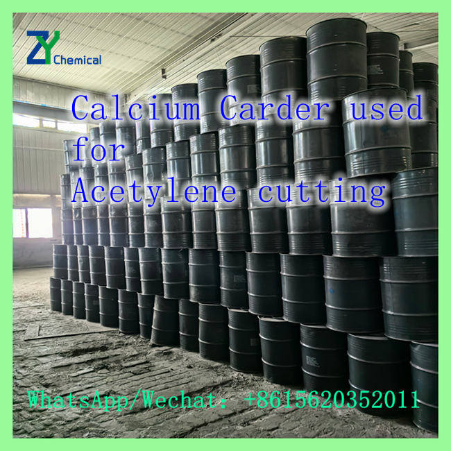 Stacked black steel drums of calcium acetylene carbide stored in warehouse for acetylene gas cutting